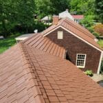 Brown shingled roof with lush greenery background.