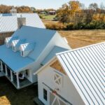 White farmhouse with metal roof in open field.