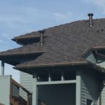 Residential building with gray roof and chimneys.