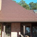 Brown shingle roof with skylight and trees