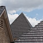 Brick house with shingle roof in sky background.