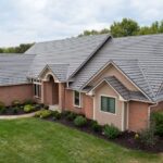 Brick house with gray shingle roofing and garden