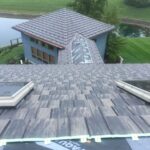 Roof with skylights overlooking house and pond view.
