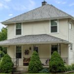 Two-story house with American flag and garden.